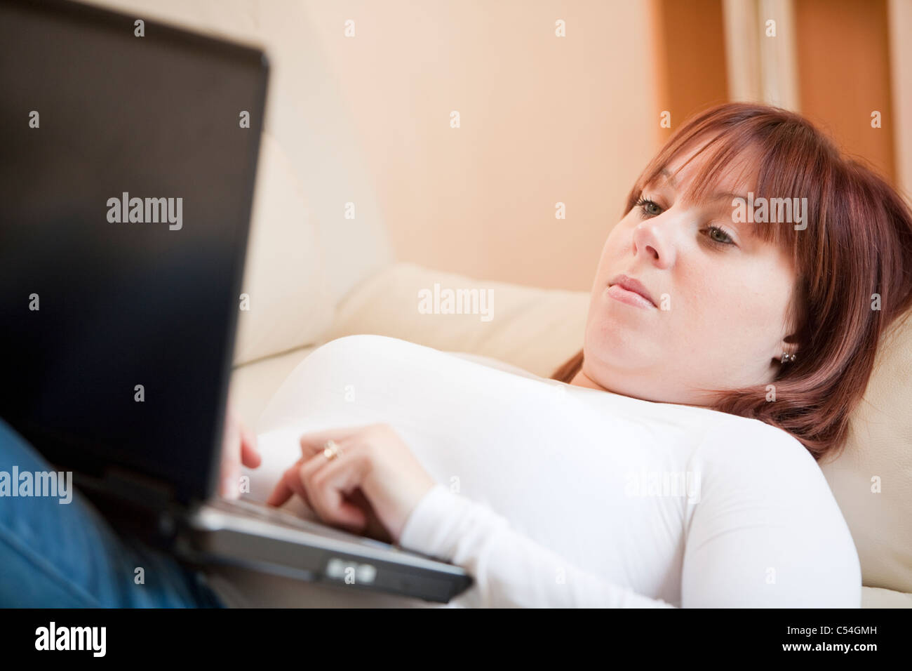 Attractive young woman relaxing on the sofa at home and surfing the ...