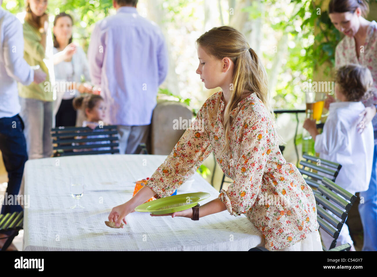Little girl cleaning dining table after eating food with family in the