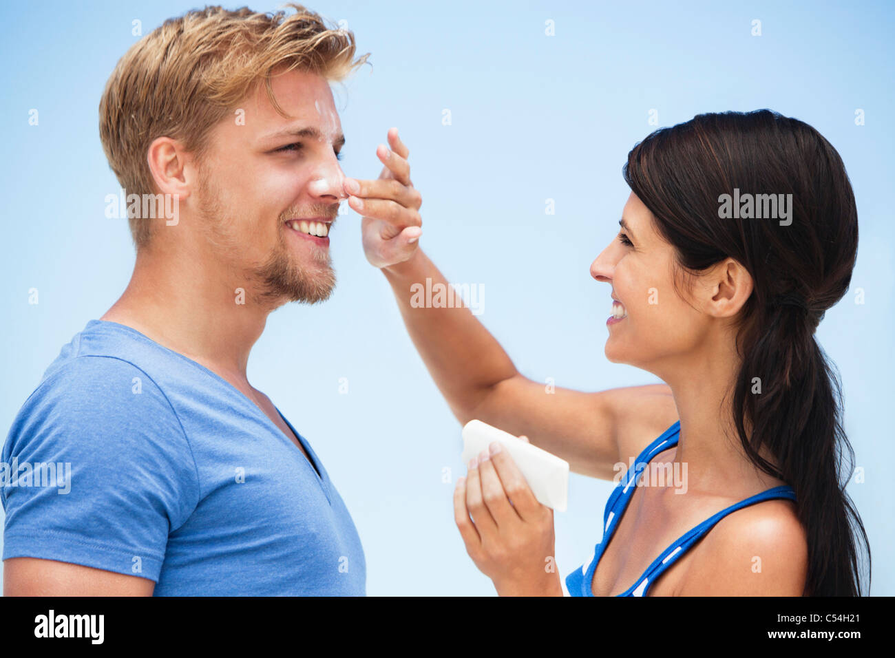 Woman applying suntan lotion on man's face Stock Photo Alamy