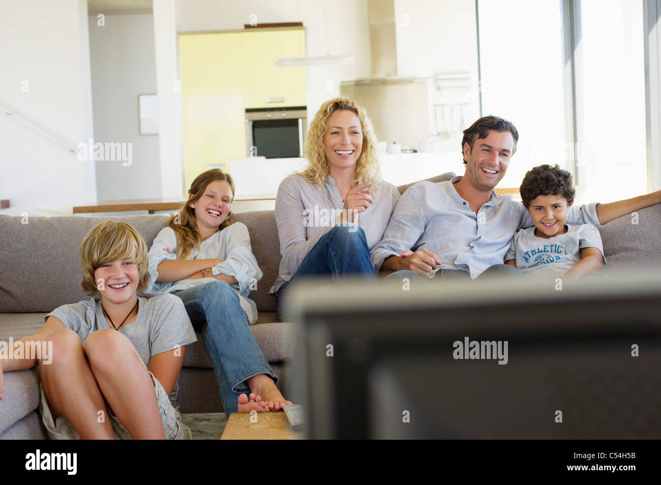 Family watching TV together at home Stock Photo - Alamy, image size:1300x954