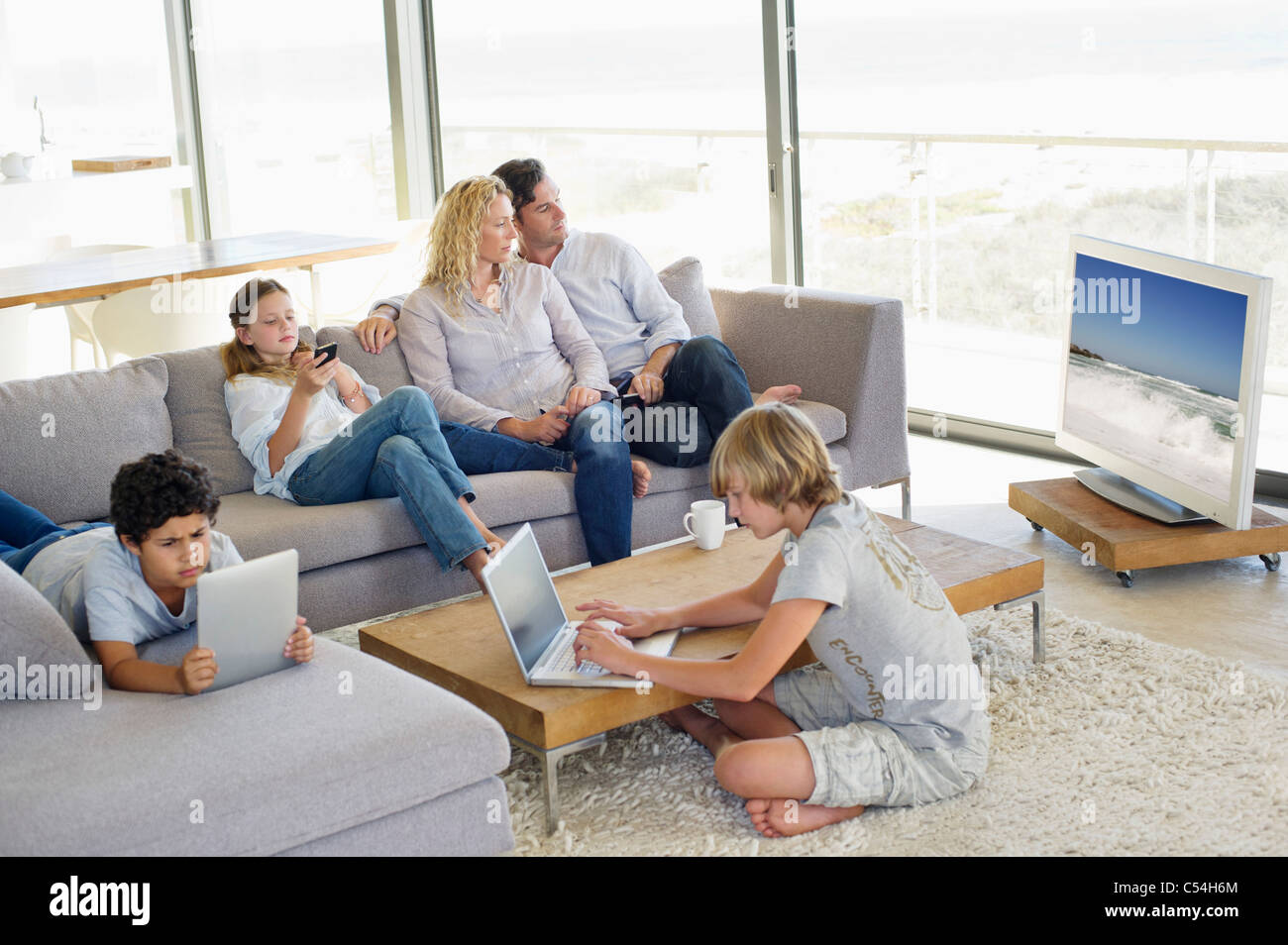 Games To Play While Watching Tv Couple watching television set while kids busy using electronic Stock
