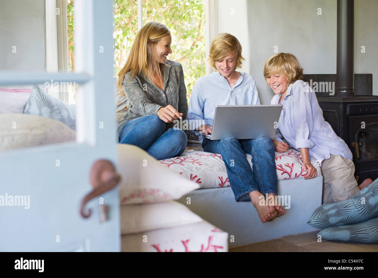 Children and their mother using laptop at house Stock Photo - Alamy