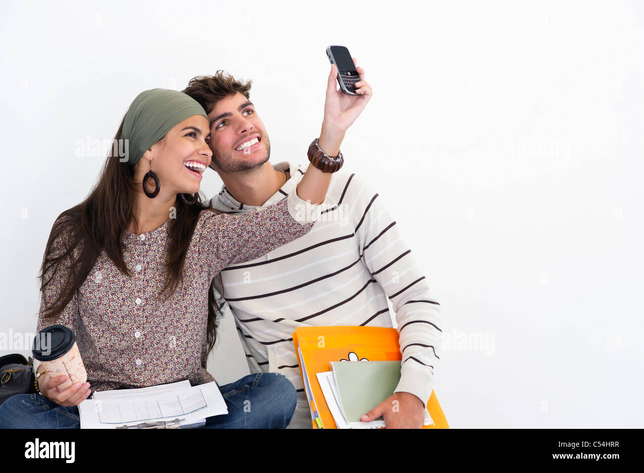 Two young friends taking photos of themselves against white background Stock Photo