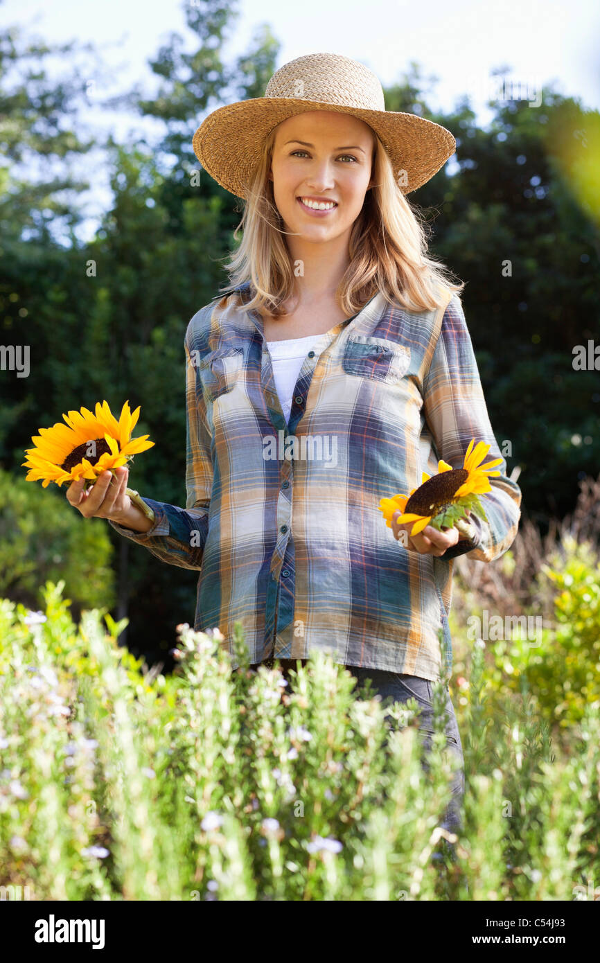 Portrait of a young woman holding sunflowers in a field Stock Photo - Alamy