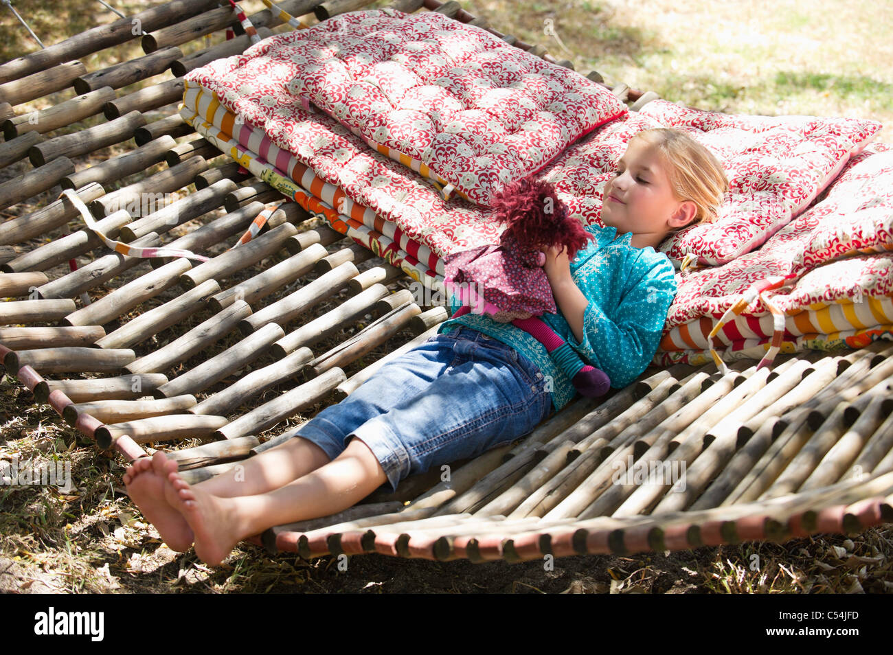 Little girl playing with toy while lying in hammock Stock Photo
