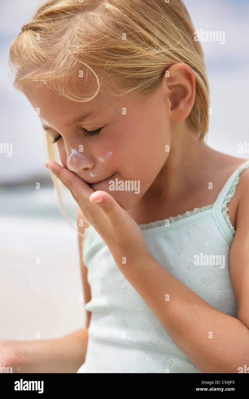 Girl applying sunscreen lotion on her face Stock Photo Alamy