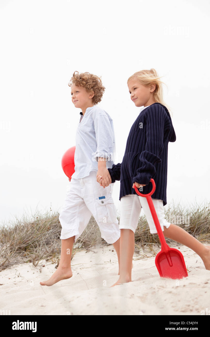 Brother and his sister walking on sand, holding hands Stock Photo - Alamy