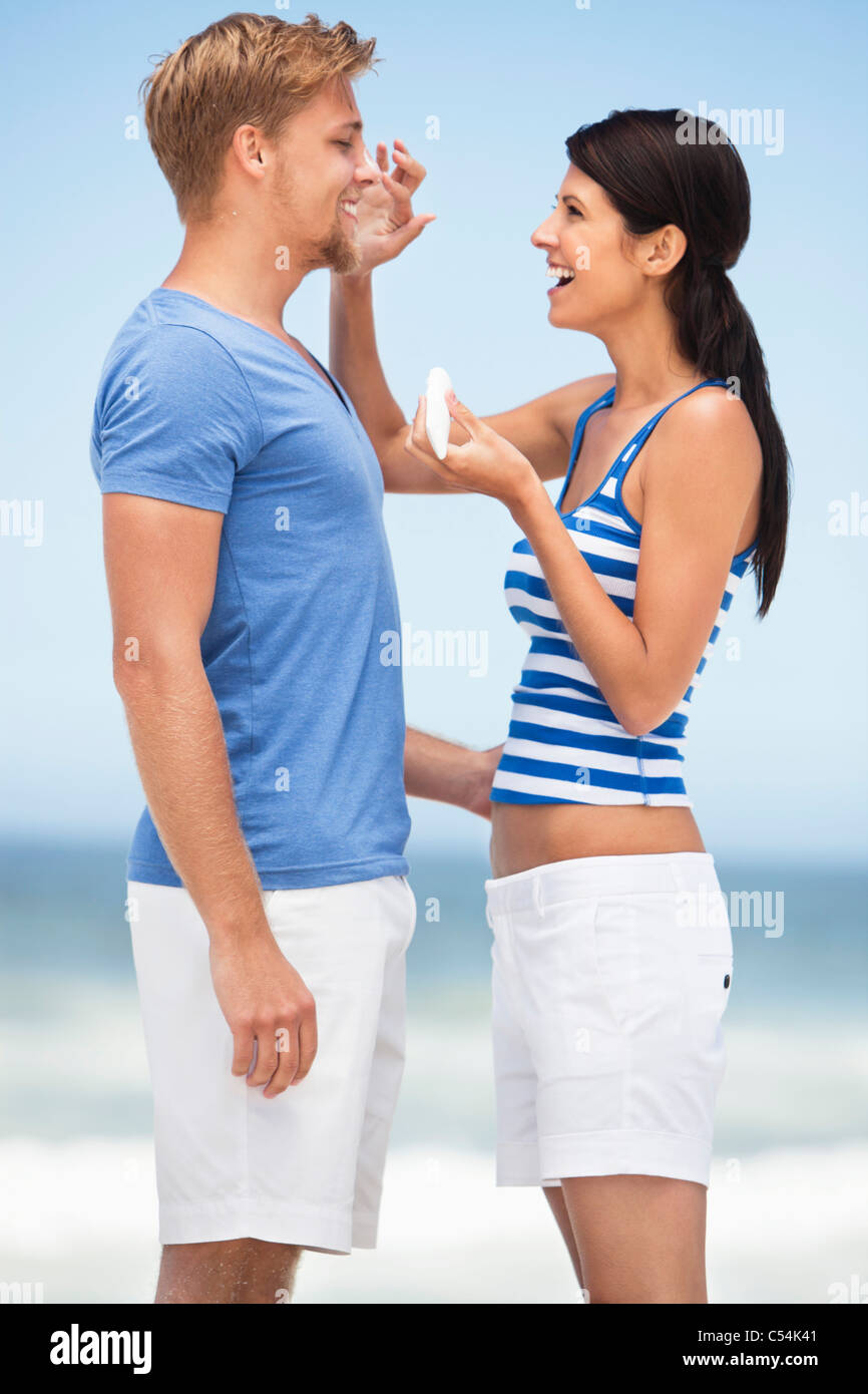Woman applying suntan lotion on man's face Stock Photo Alamy