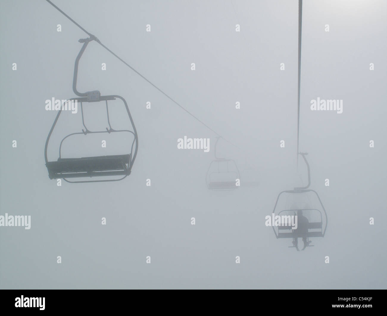 A skier sits on a chairlift in the mist in the French resort of Morillon in the Grand Massif region of the Rhone Alpes Stock Photo