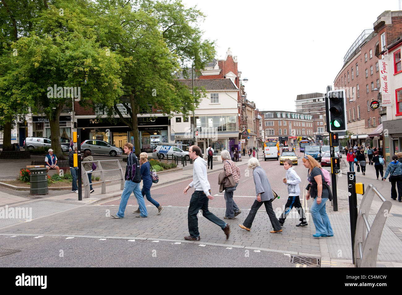 People crossing a pedestrian crossing whilst the traffic lights are still on green in Norwich city centre, England. Stock Photo