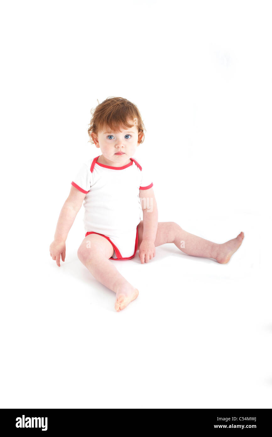 female toddler sat on floor looking at camera on isolated white ...