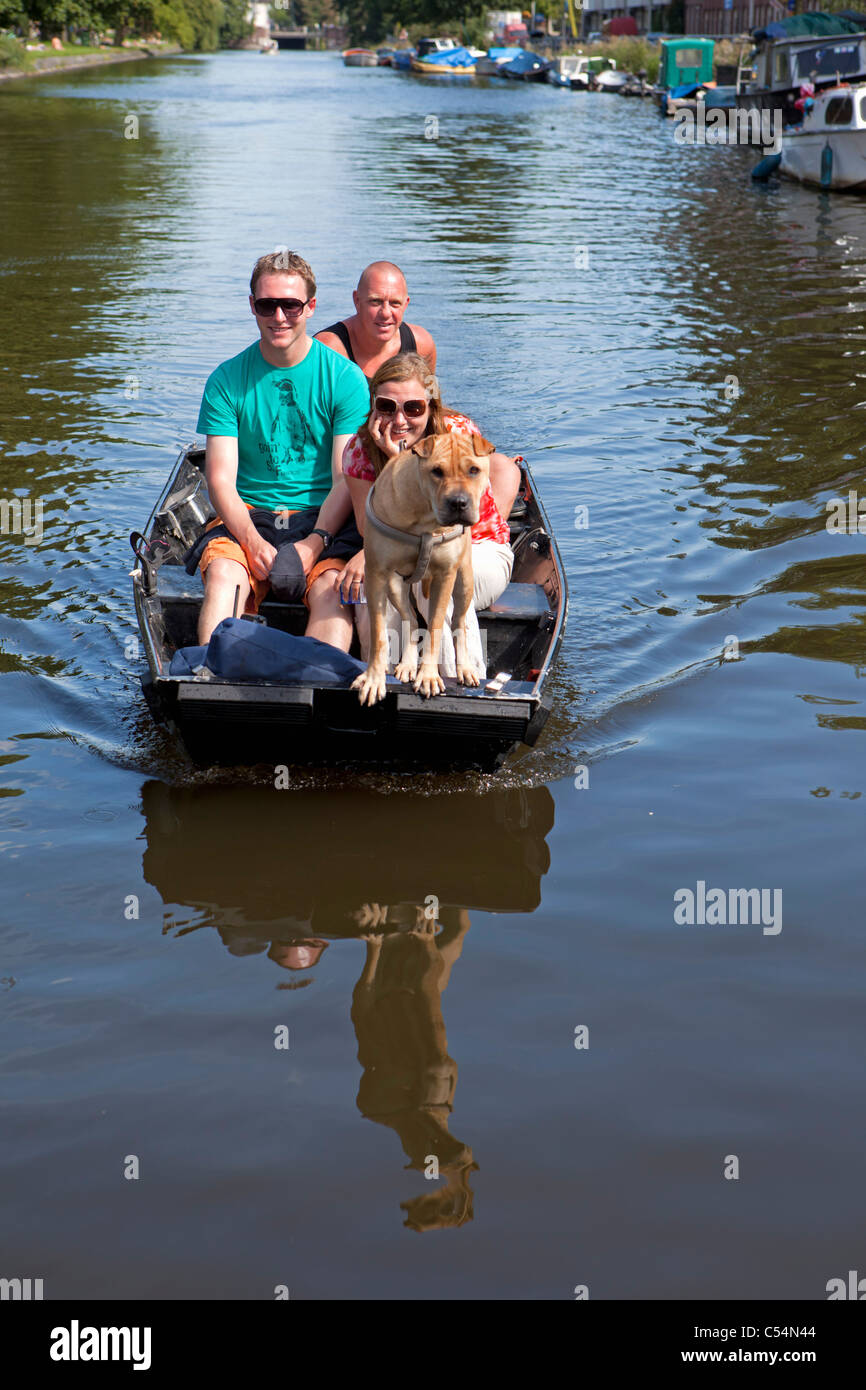 The Netherlands, Amsterdam, People and dog in small boat. Stock Photo