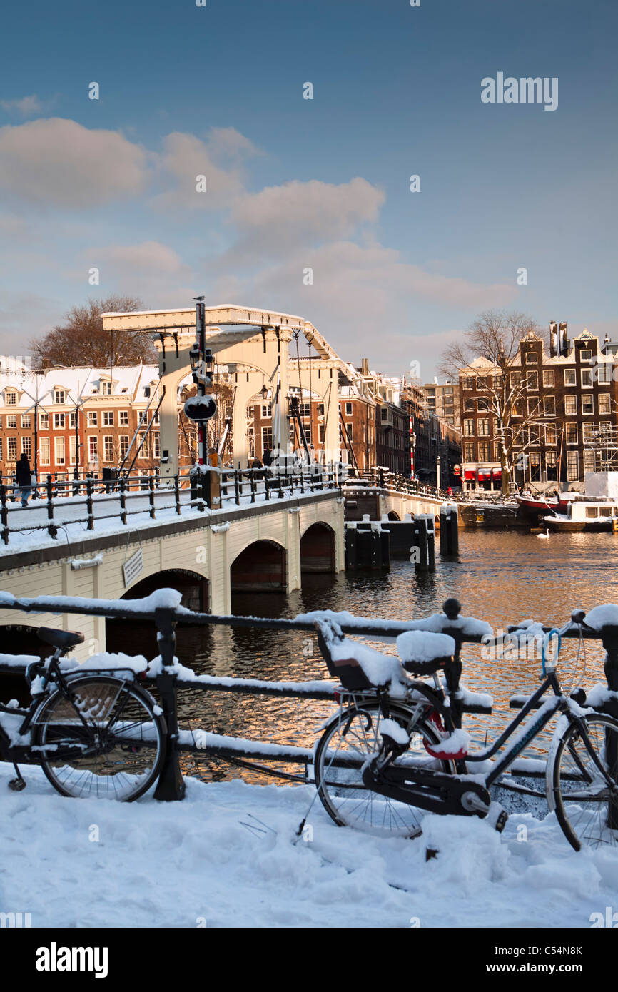 The Netherlands, Amsterdam, 17th century houses at river called Amstel. Background Skinny Bridge. Winter, snow. Stock Photo
