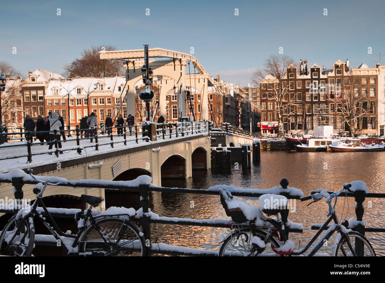 The Netherlands, Amsterdam, 17th century houses at river called Amstel. Background Skinny Bridge. Winter, snow. Stock Photo