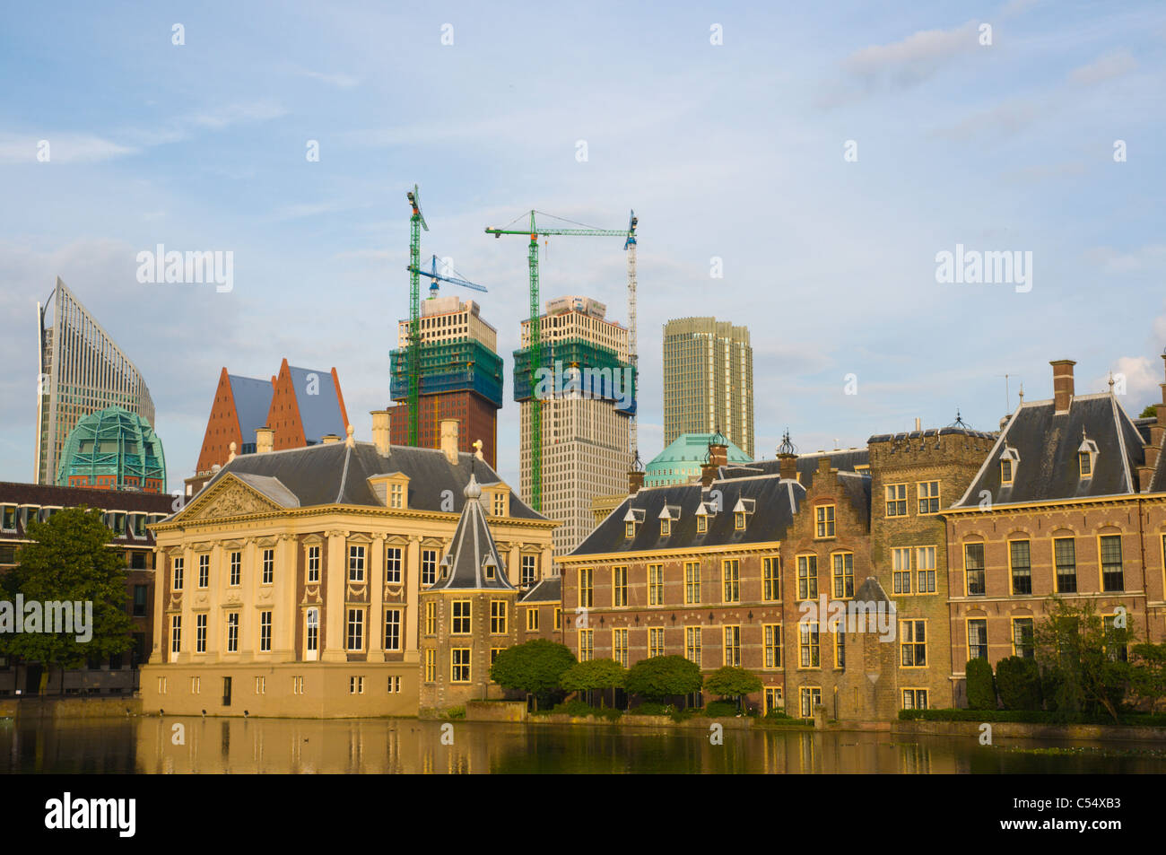 Construction cranes behind Mauritshuis and Binnenhof palace complex by Hofvijver lake Den Haag the Hague the Netherlands Europe Stock Photo