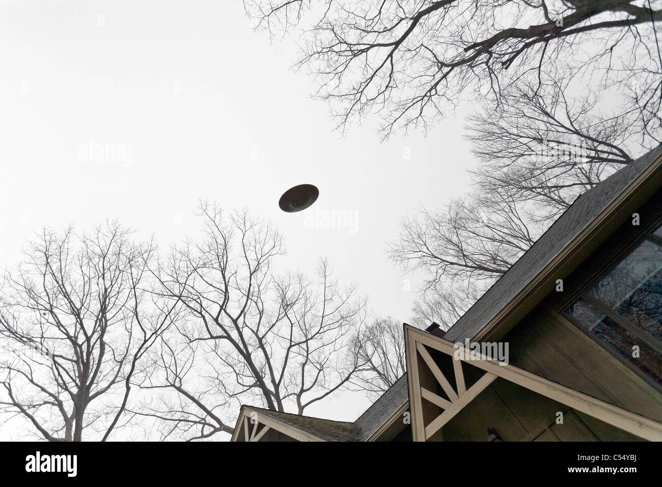 UFO flying over a house. Stock Photo