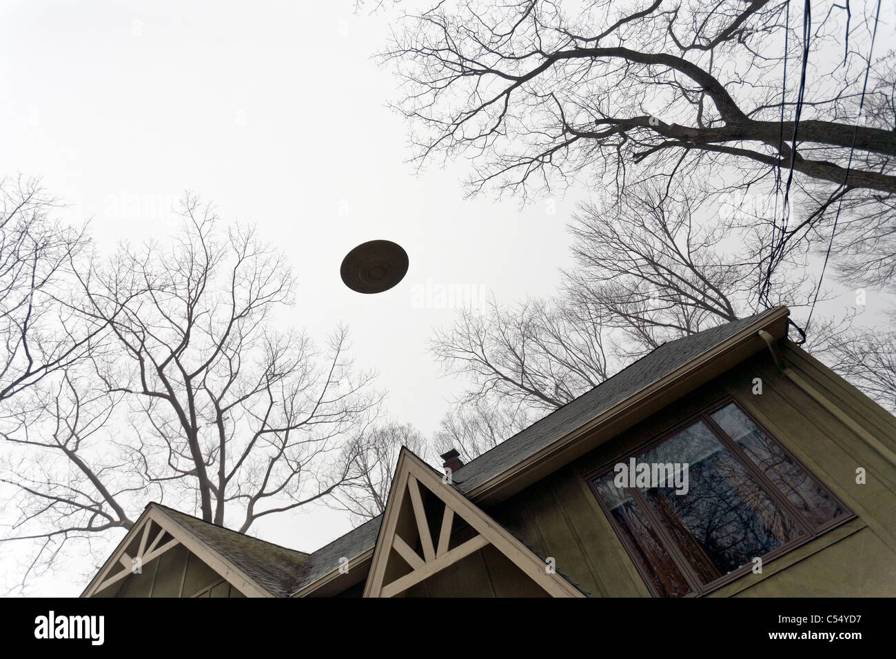 UFO flying over a house. Stock Photo