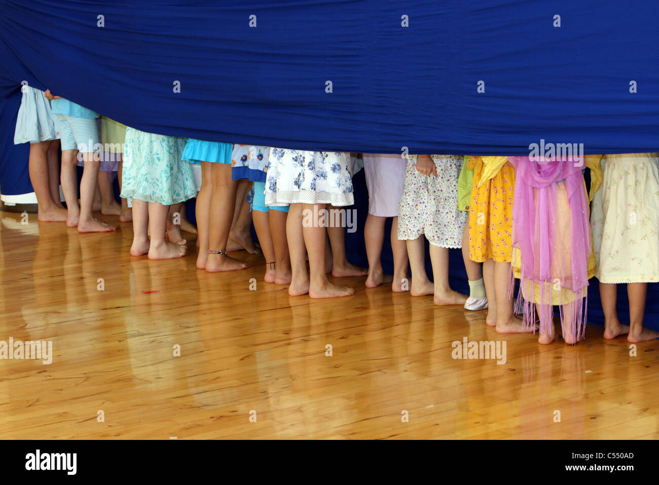 Children hiding behind a blue curtain Stock Photo