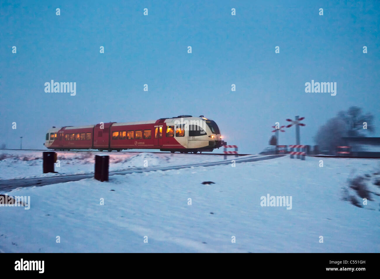 The Netherlands, near Sneek, Local train in snow landscape at dawn. Stock Photo