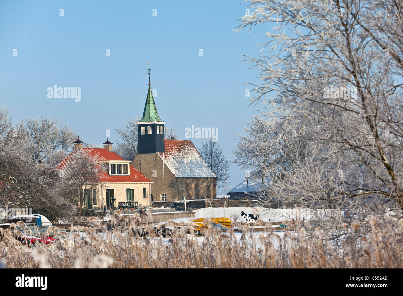 The Netherlands, Piaam, View of church and houses in frost and snow. Stock Photo
