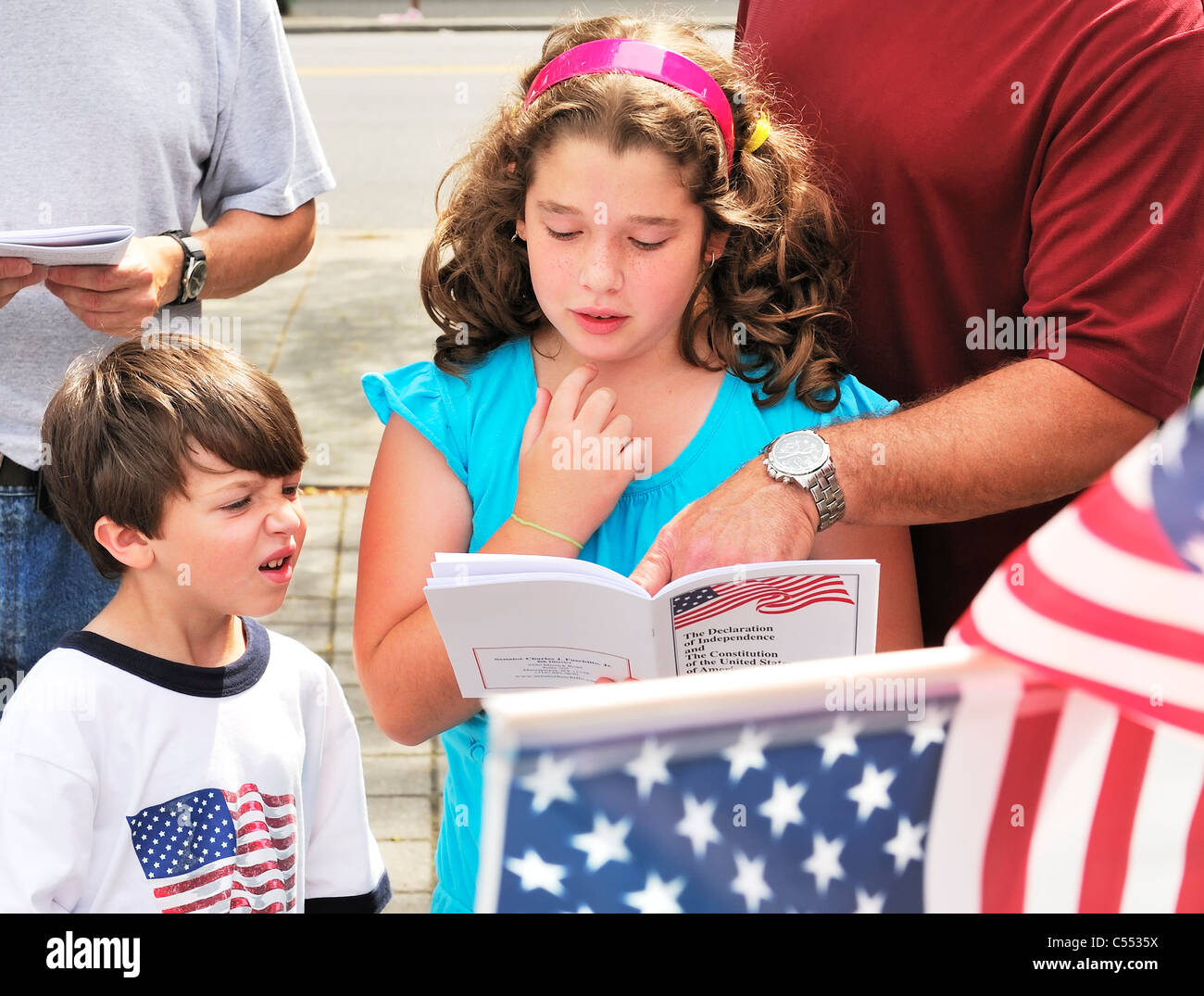 Patriotic young girl reading Declaration of Independence at July 4th Celebration, with father pointing to place on page, 2011 Stock Photo