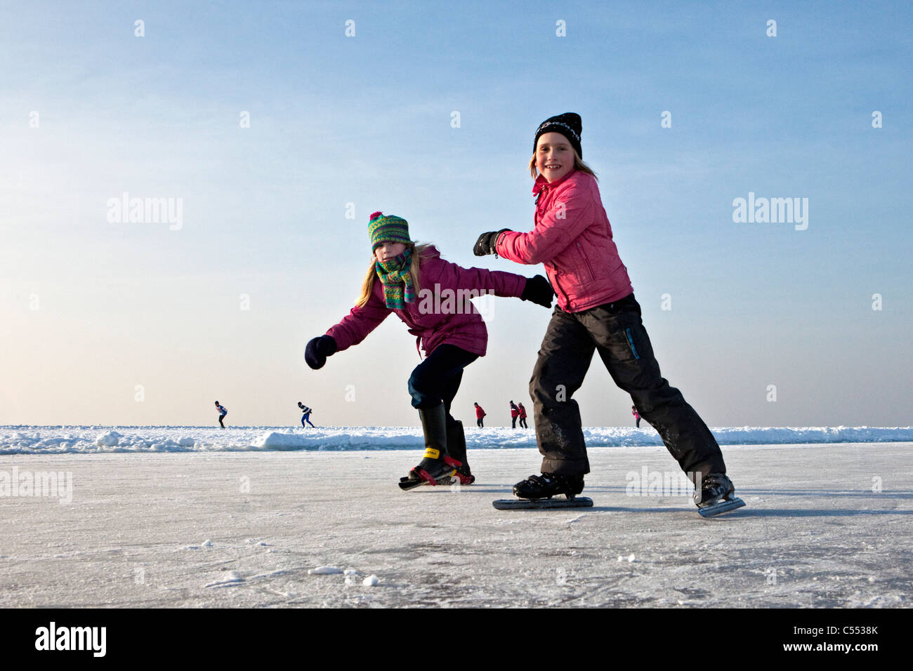 The Netherlands, Hindeloopen, children ice skating on lake called IJsselmeer. Stock Photo