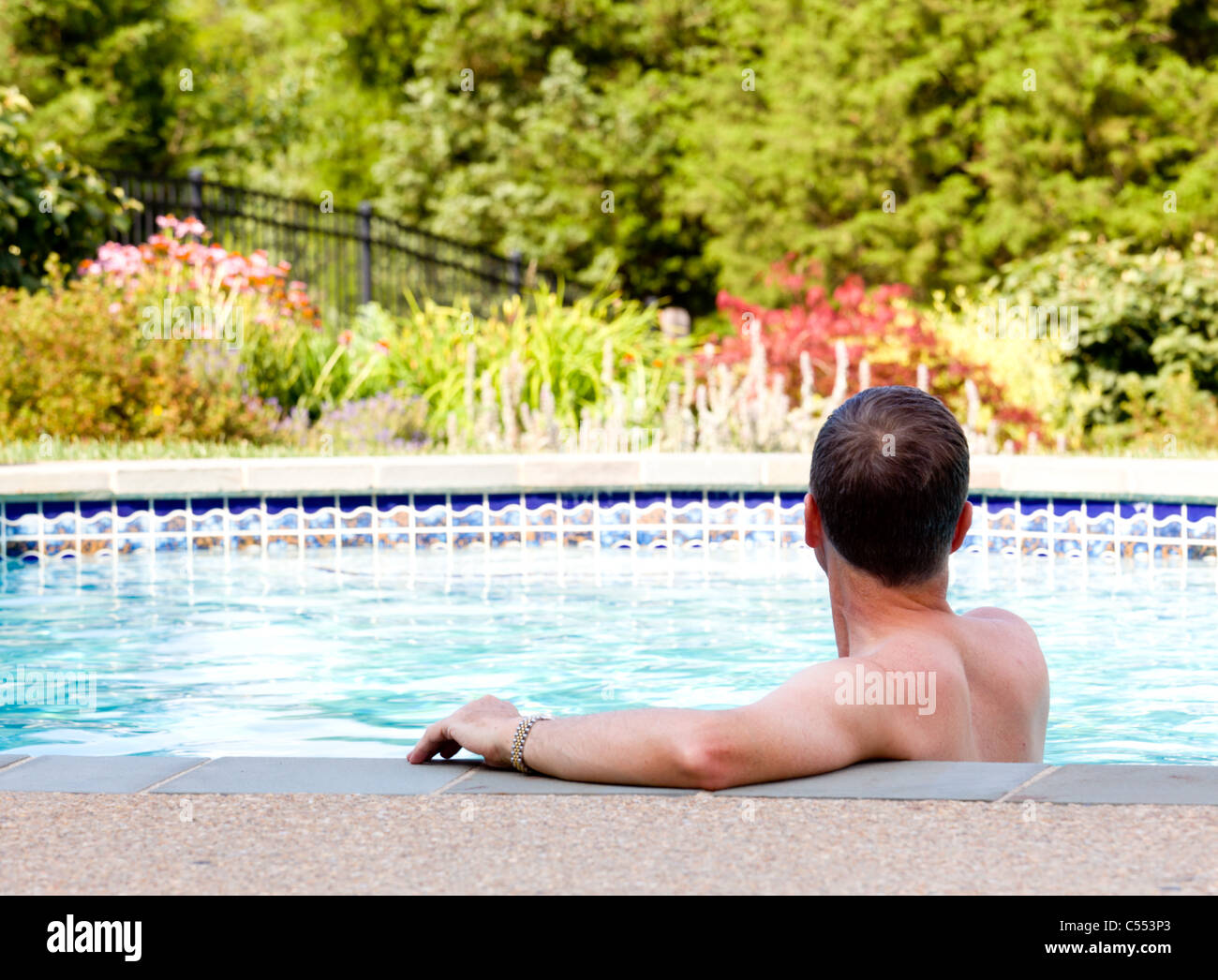 Man Relaxing By The Side Of A Swimming Pool At Home In The Garden And Stock Photo Alamy