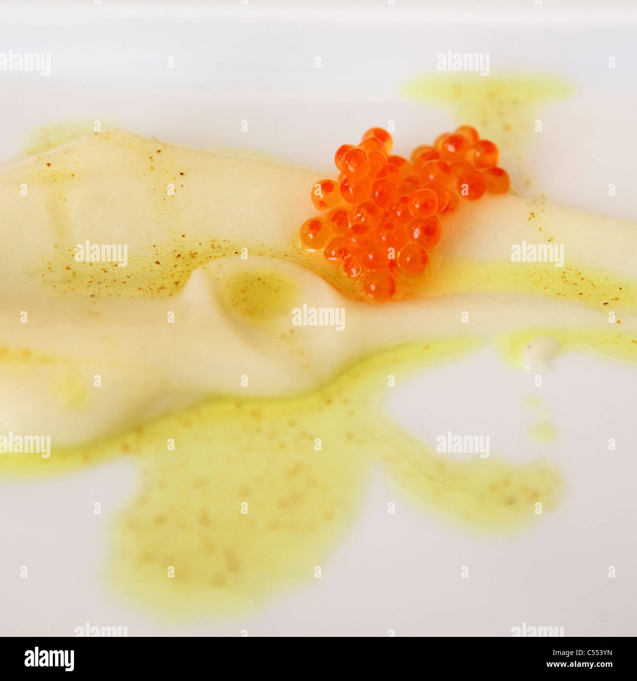 Cream of cauliflower is served with salmon roe and spiced olive oil. Stock Photo