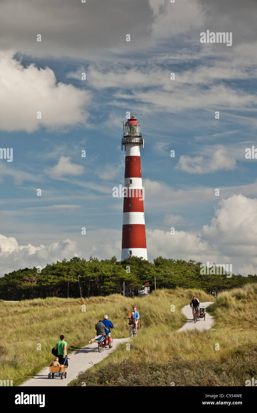 The Netherlands, Hollum, Ameland Island. People on bicycle on beach road. Lighthouse. Stock Photo
