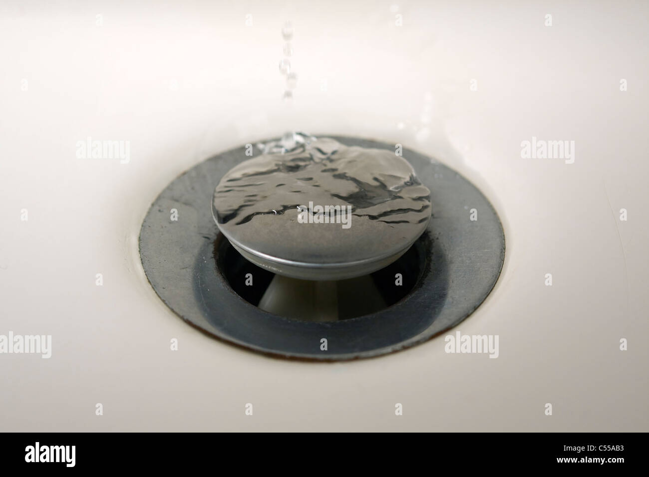Ripples made by water dripping on a drain plug in a bathroom sink Stock