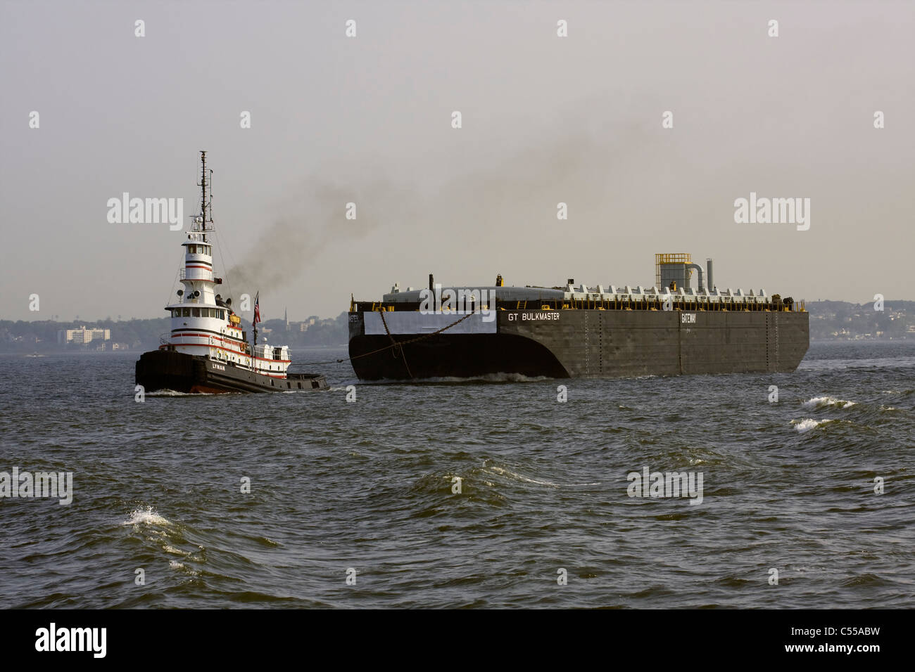 Tugboat 'LYMAN' with second pilothouse towing a barge 'GT BULKMASTER' in New York Harbor Stock Photo