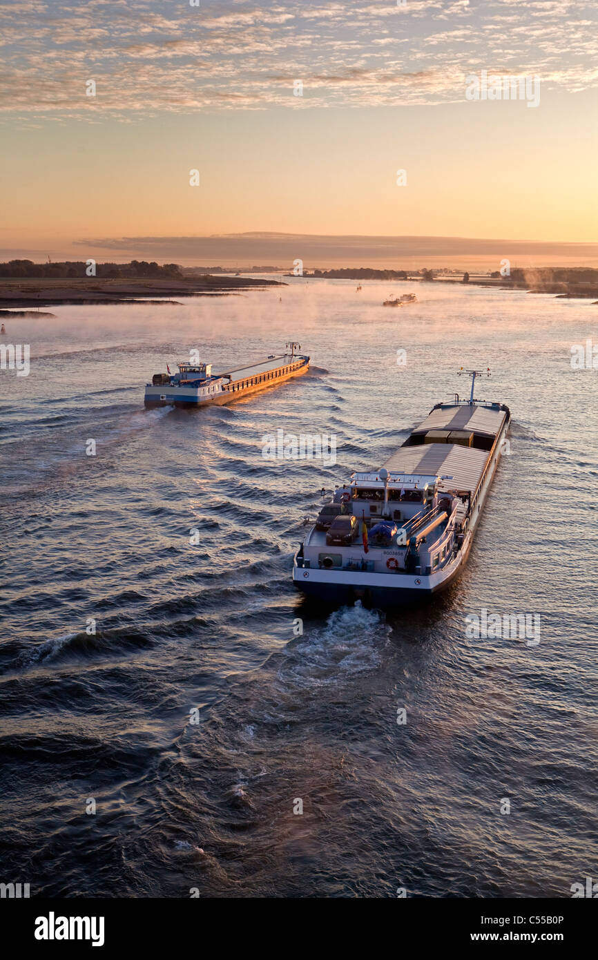 The Netherlands, Nijmegen, Cargo boats on Waal river. Sunrise. Stock Photo