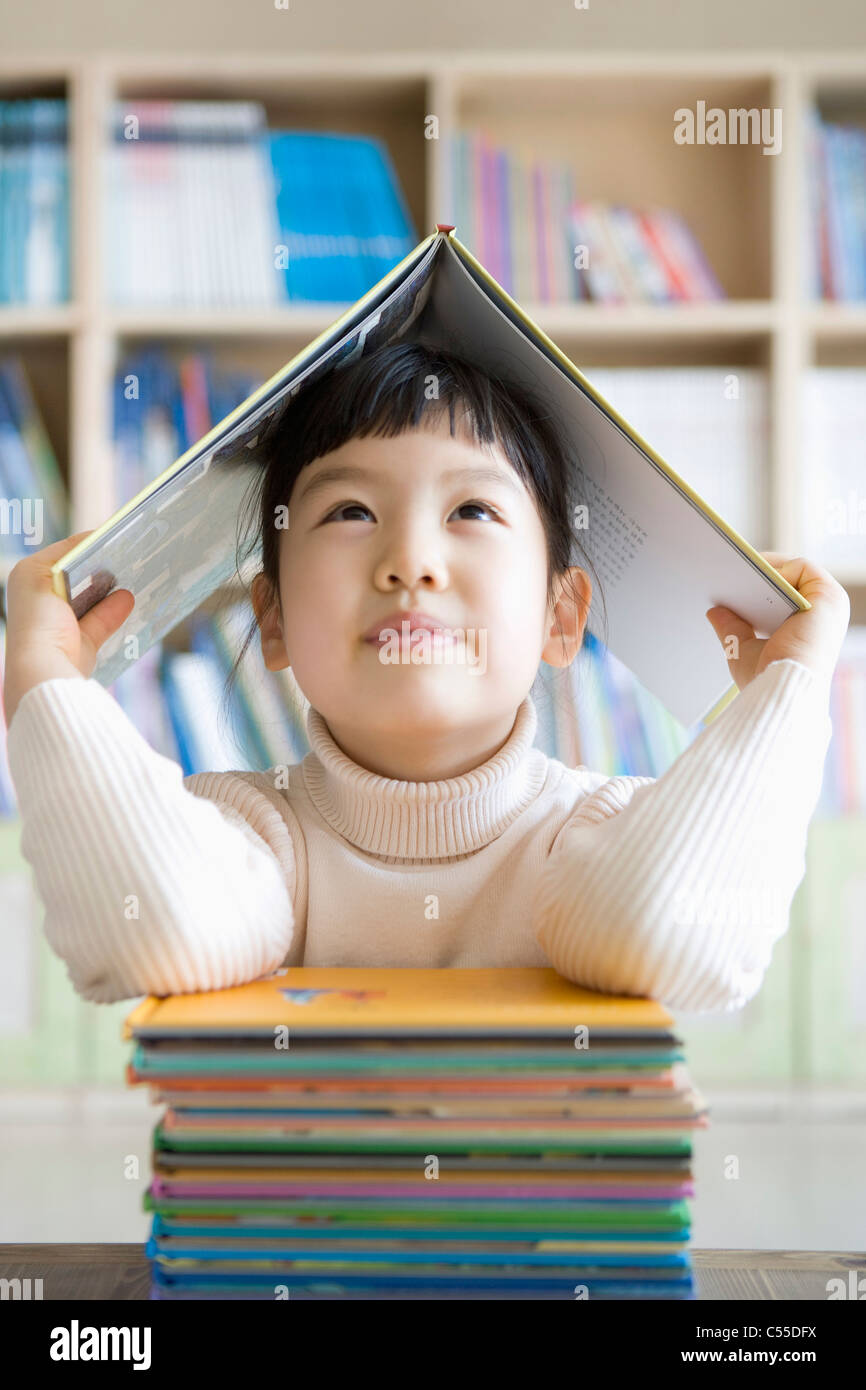 girl is holding the book over her head Stock Photo - Alamy