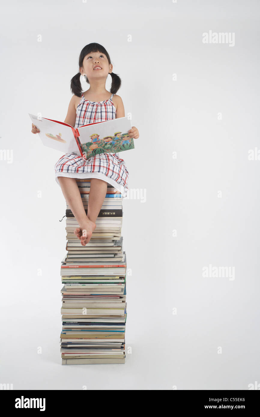 A girl sitting on the pile of books Stock Photo - Alamy