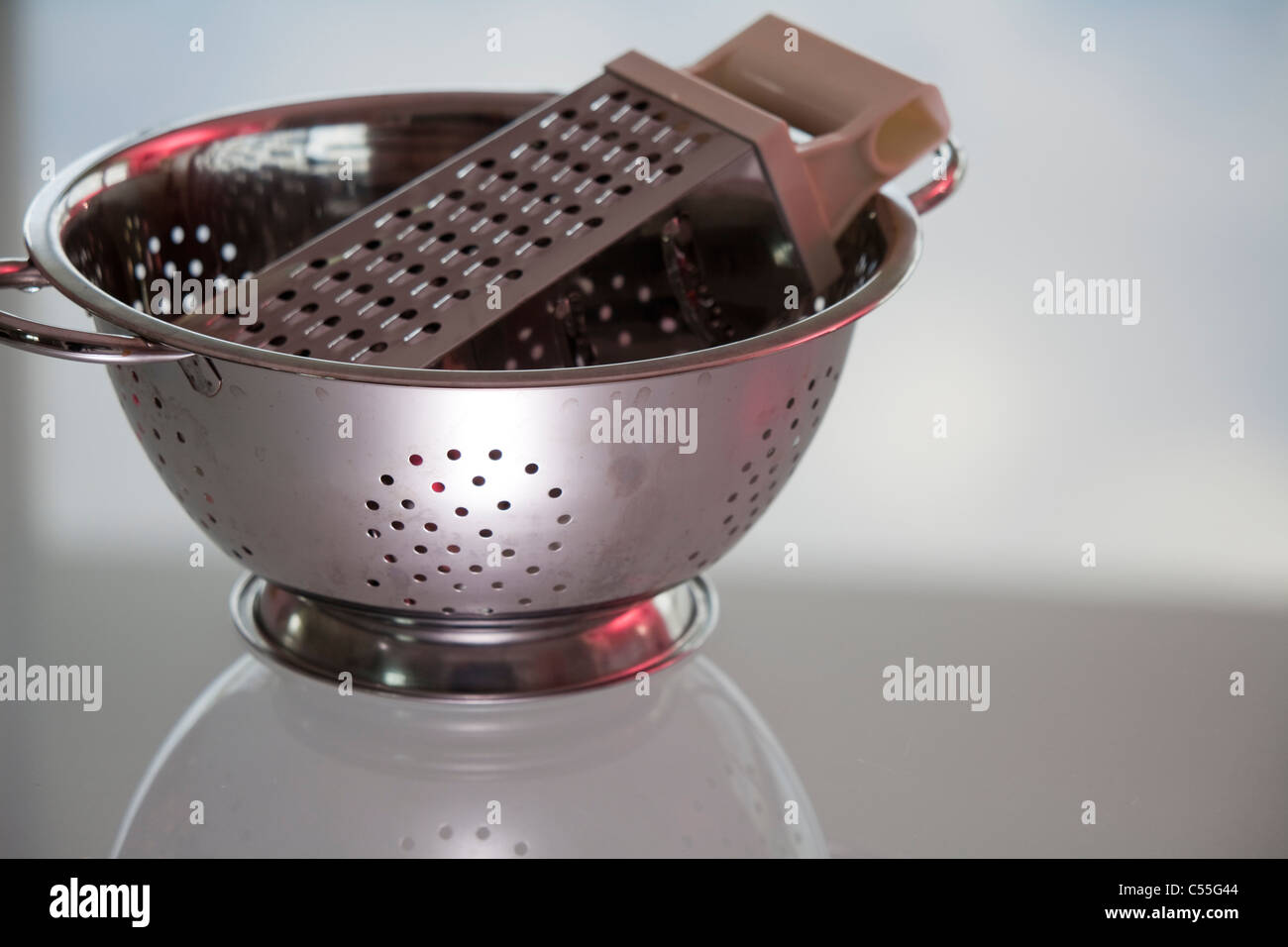 Grater in a colander on a table Stock Photo Alamy