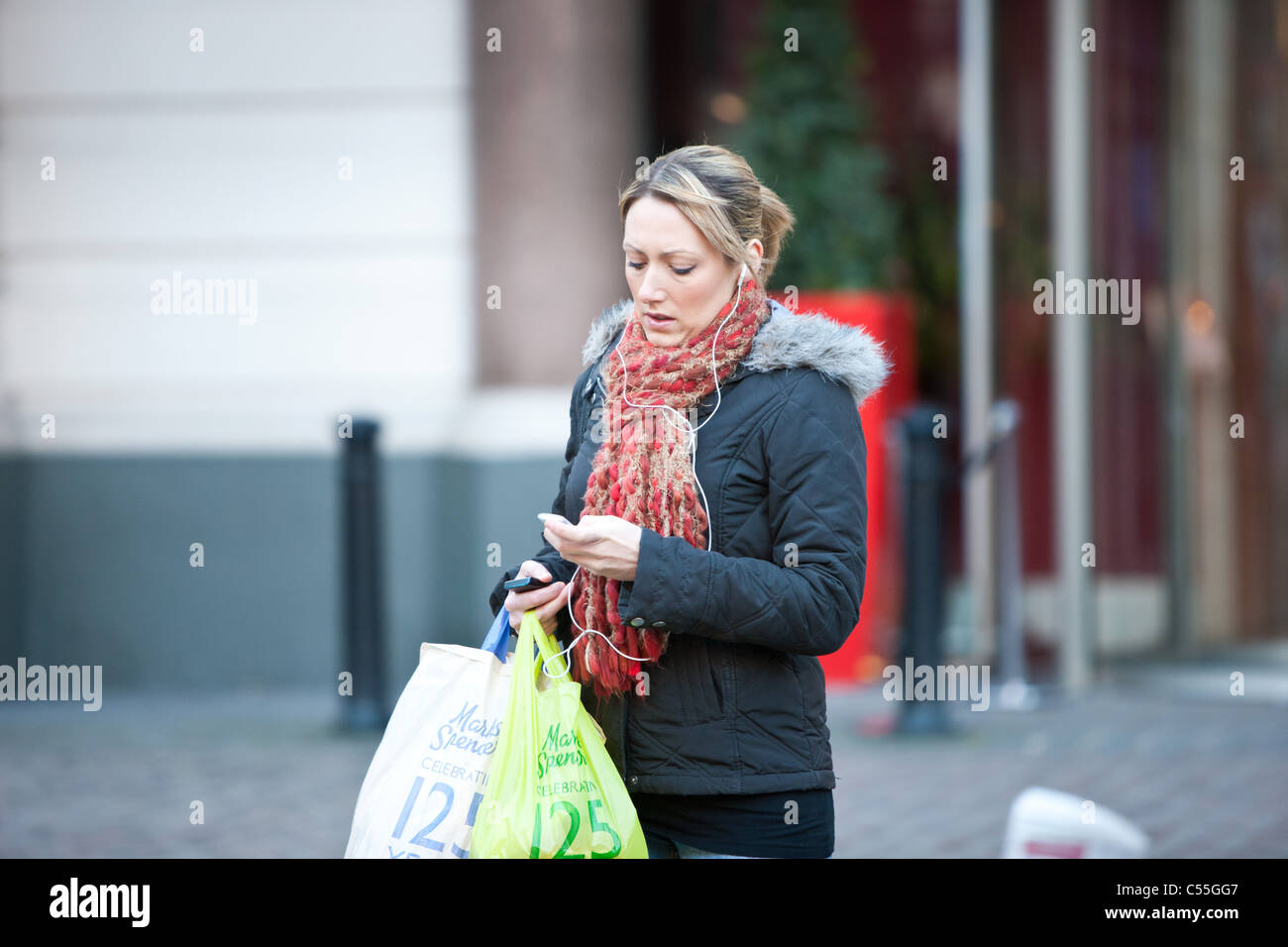 woman on mp3 player carrying bags Stock Photo