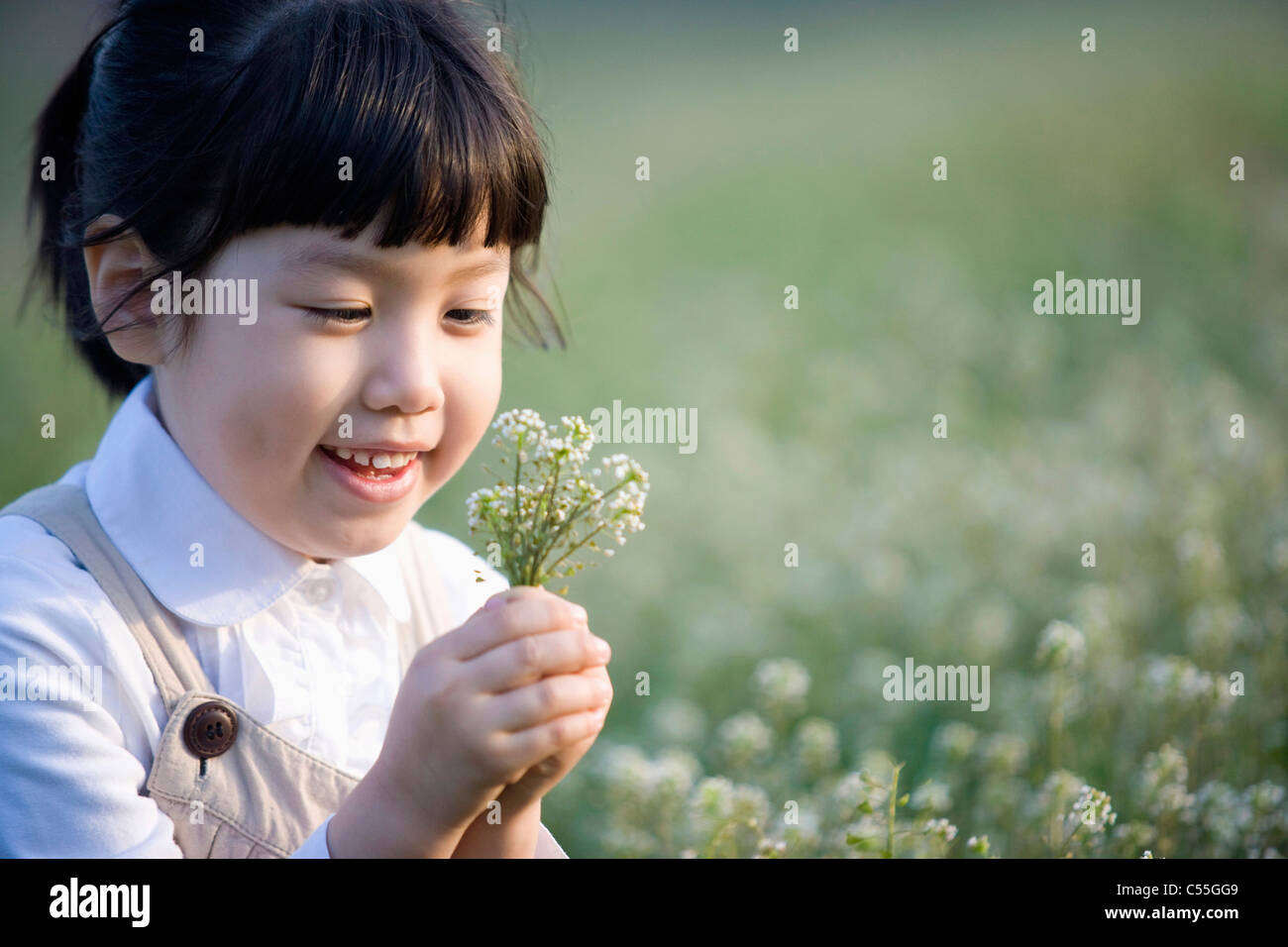 girl holding a flower with a smile Stock Photo - Alamy