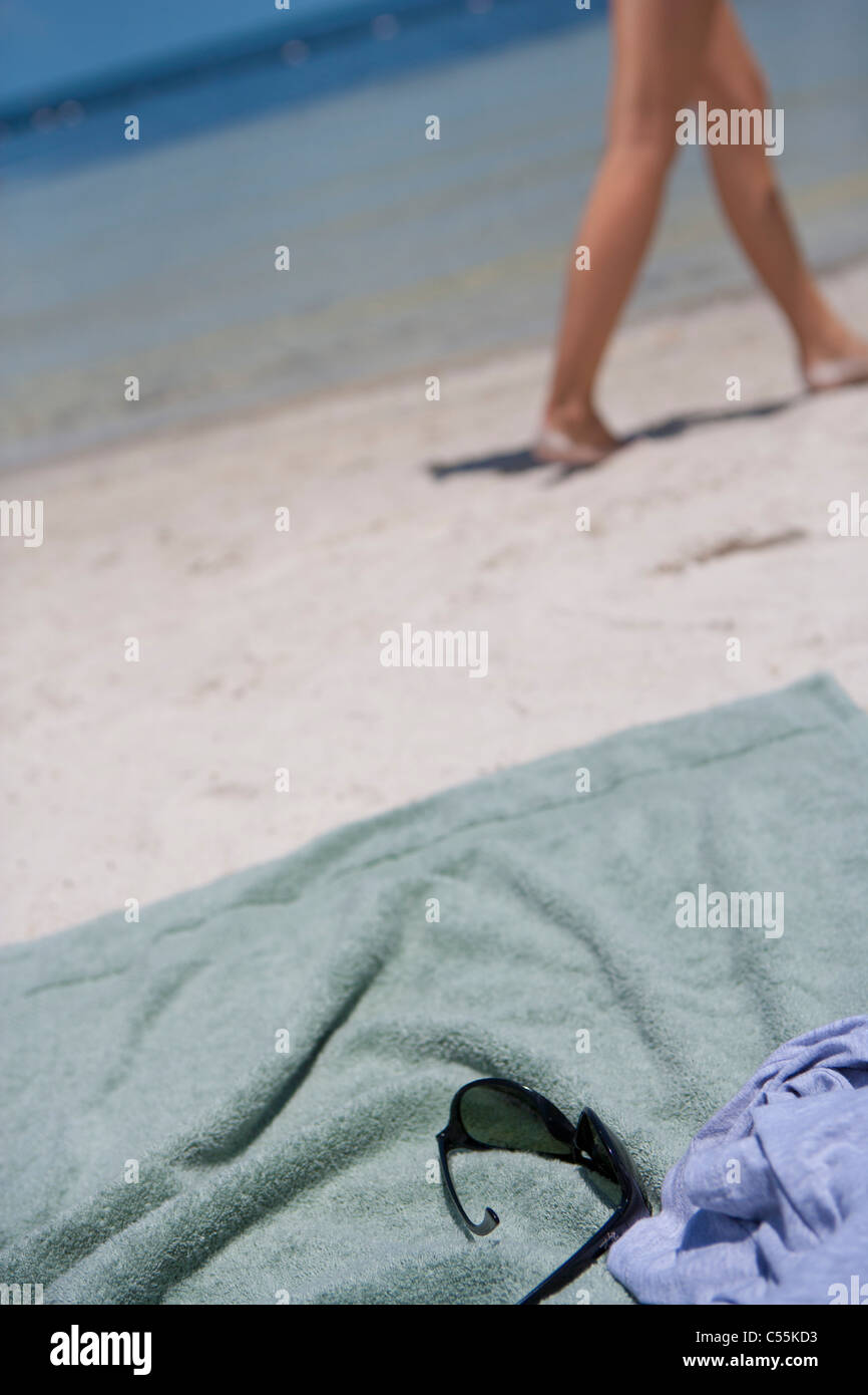 Towel on the beach with woman walking in the background Stock Photo Alamy