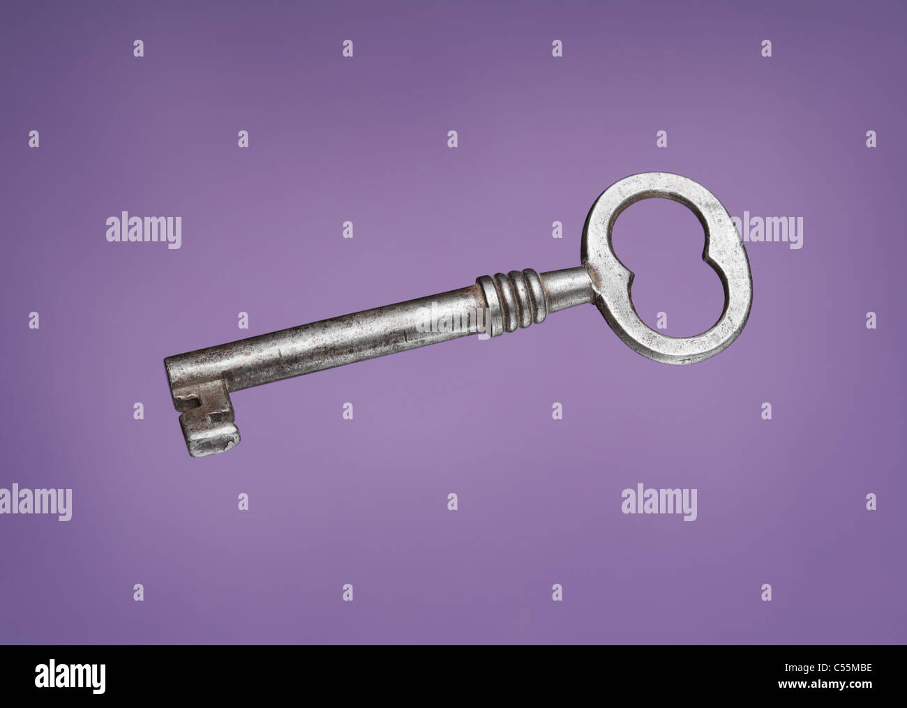 Old metallic key on lila background Stock Photo