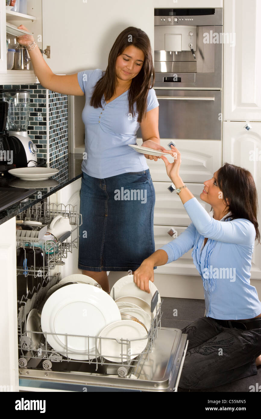 Two friends in the kitchen unloading the dishwasher Stock Photo
