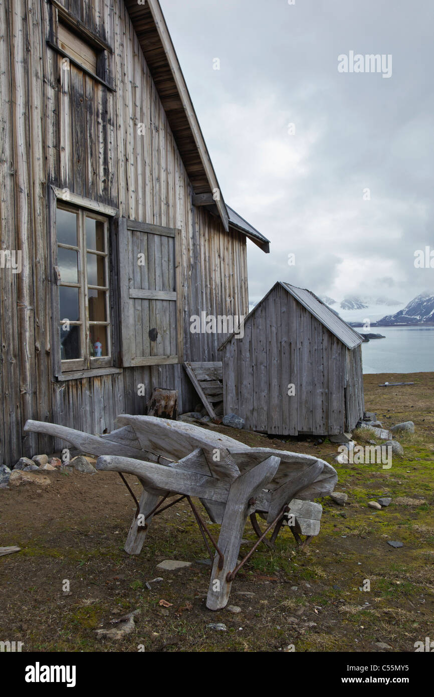 Old wooden trapper's hut and wheelbarrow, Camp Mansfield, Blomstrandhalvoya, Spitsbergen, Svalbard Islands, Norway Stock Photo
