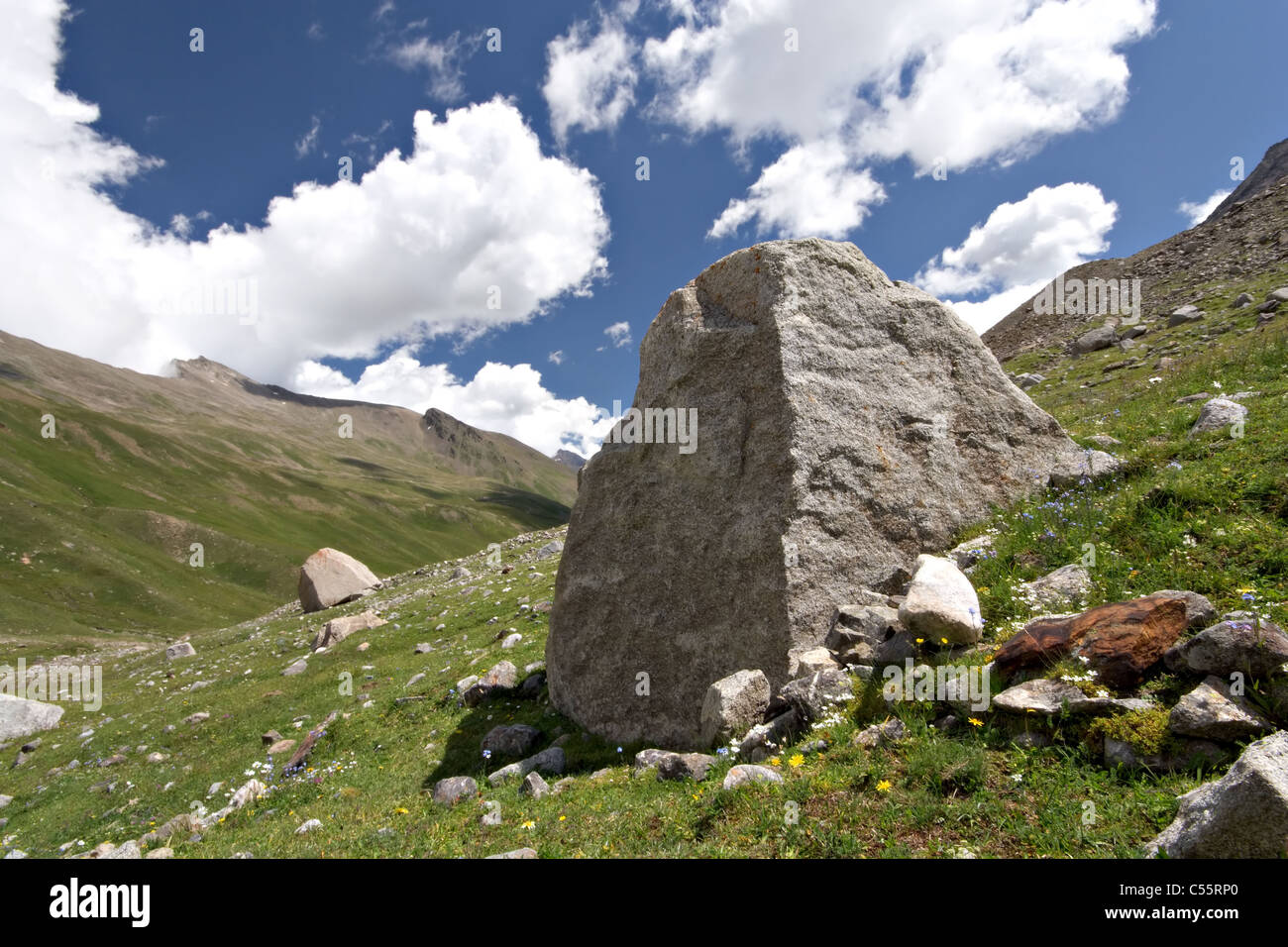 Huge stone boulder in Caucasus valley. Blue sky with clouds. Elbrus area. Kabardino-Balkaria. Stock Photo