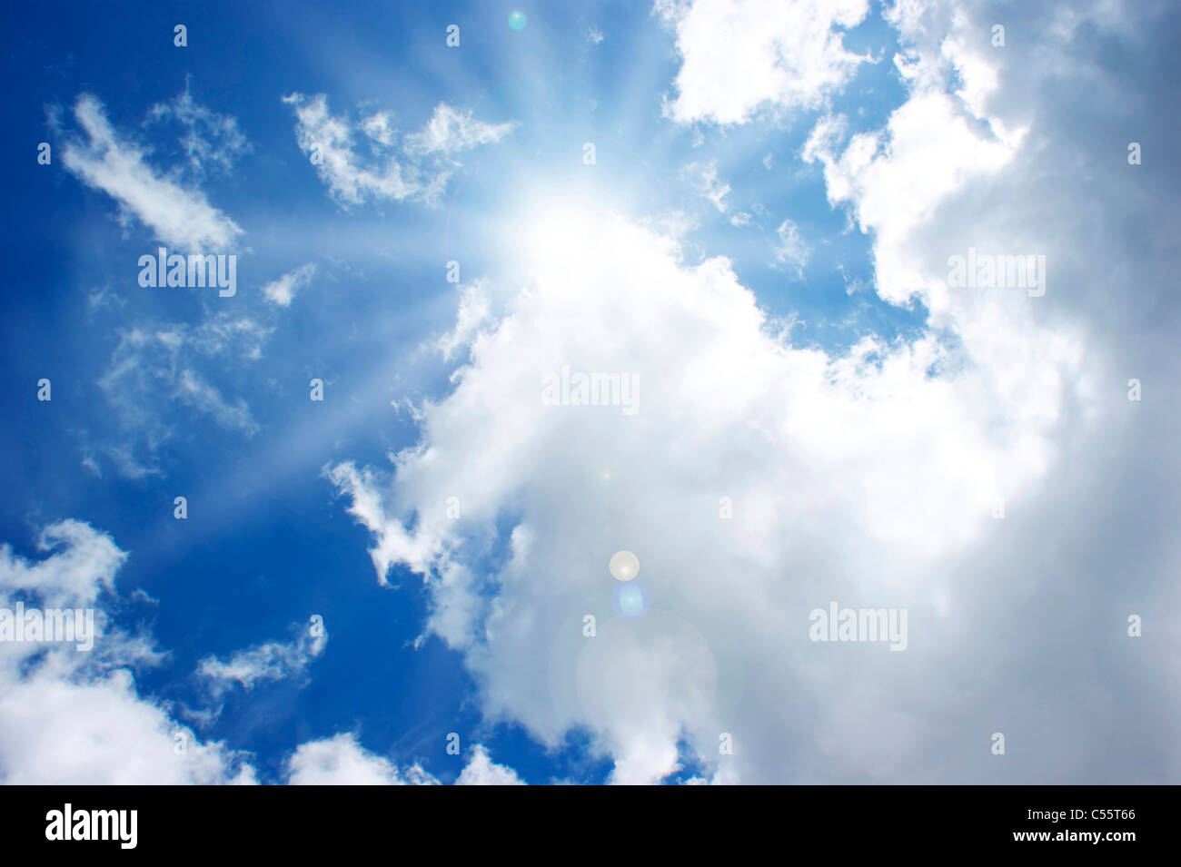 Sunshine in a blue sky with fluffy white clouds Stock Photo - Alamy