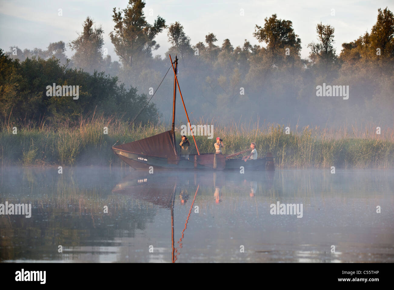 Netherlands, Werkendam, Biesbosch National Park. Fishing scow, called Zalmschouw, sternpost, People enjoying nature at sunrise. Stock Photo