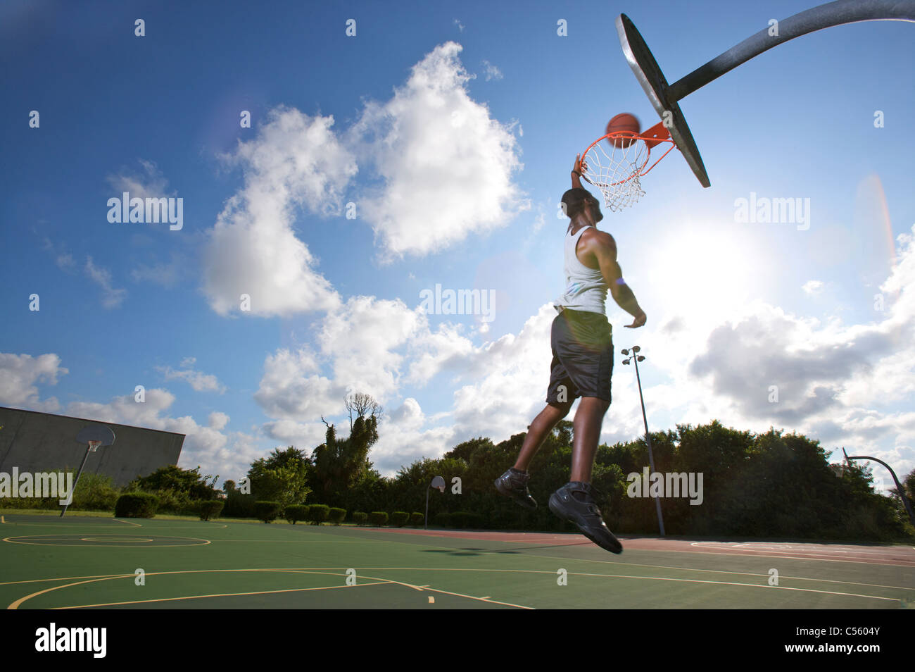 male making slam dunk during outdoor basketball game, upward view Stock Photo