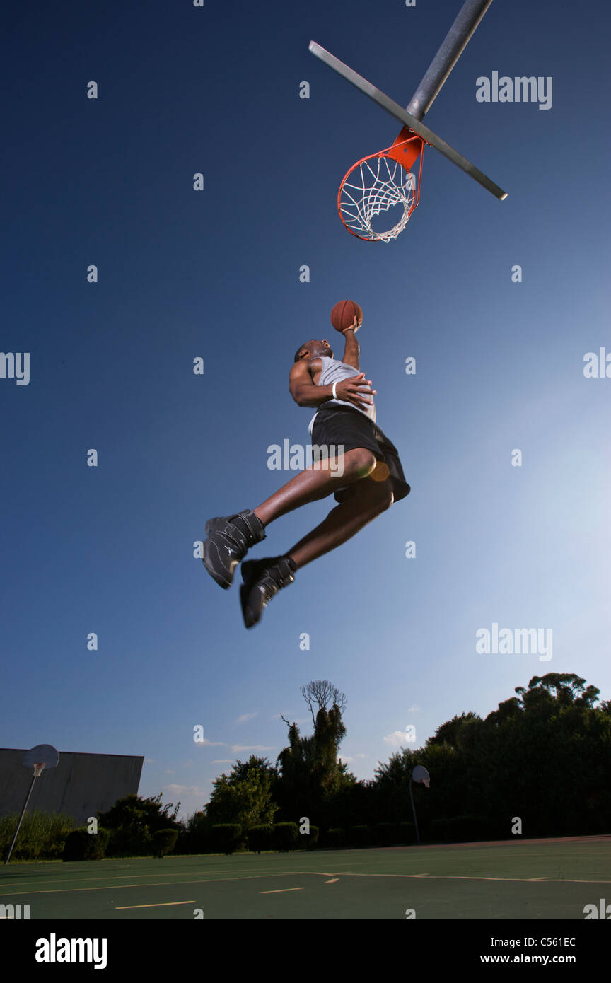 male making  dunk, layup on outdoor basketball goal Stock Photo