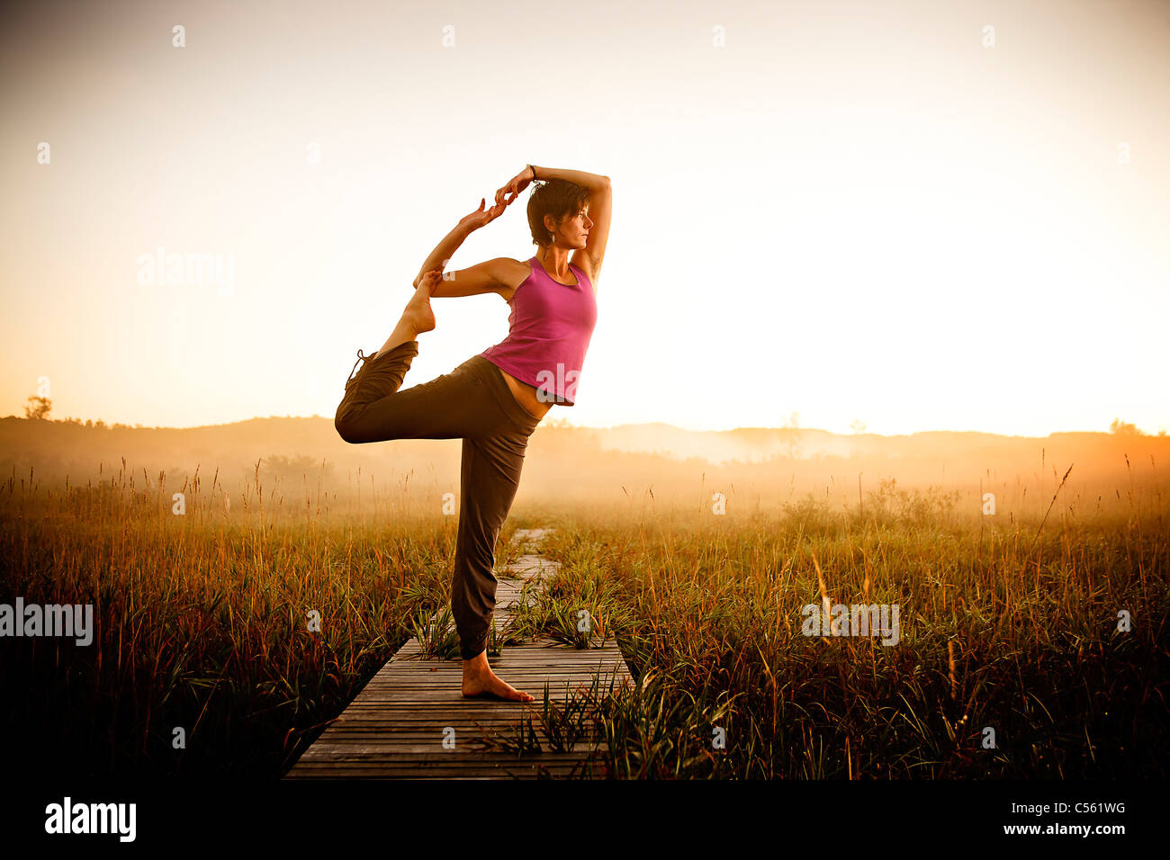 Mid adult woman doing morning yoga in a field, Upper Herring Lake