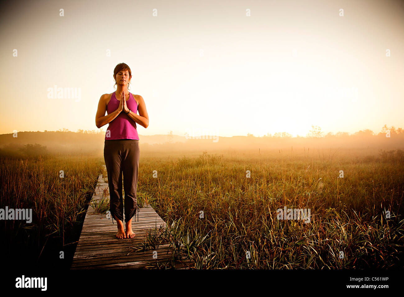 Woman meditating at a lake 30 35 years hires stock photography and