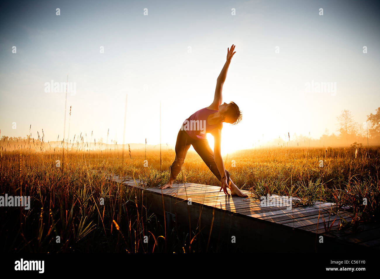 Mid adult woman doing morning yoga in a field, Upper Herring Lake