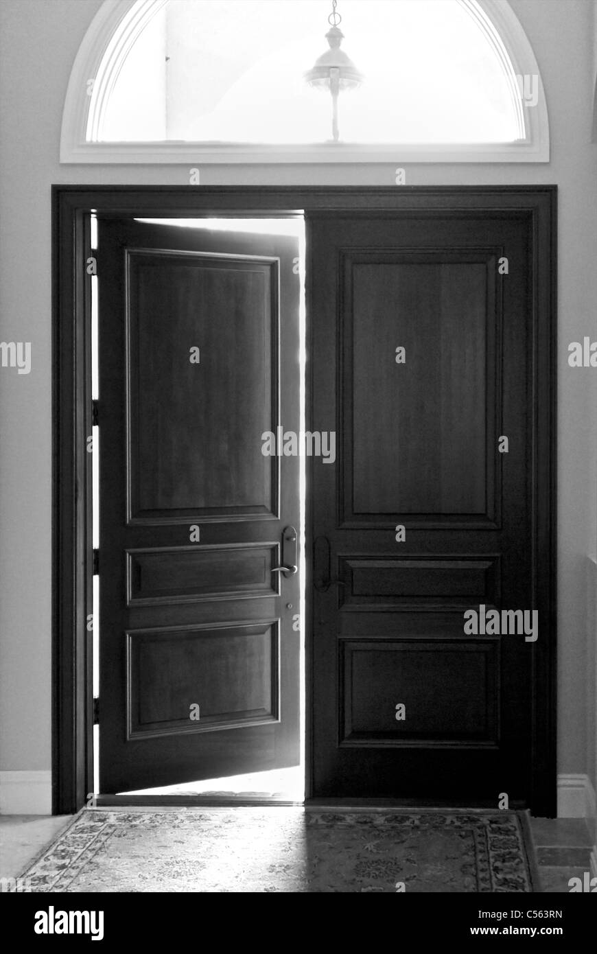 A set of heavy wooden doors with one of them open leading outside with